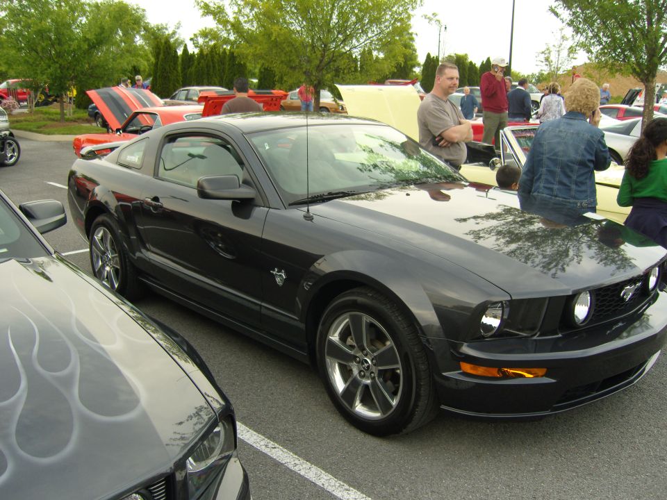 Dark gray 2007 Ford Mustang parked at a car show, with another car's front end visible on the left