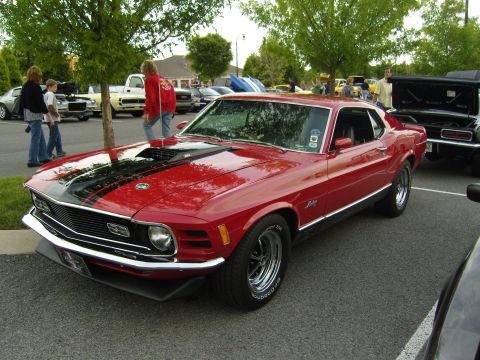 2007 Ford Mustang - A classic red 1970 Ford Mustang Mach 1 is displayed at an outdoor car event with other vehicles present.