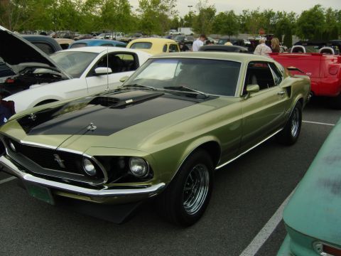 2007 Ford Mustang - A classic green 1969 Ford Mustang is parked at a car show next to other vehicles.