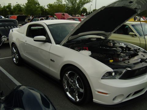 2007 Ford Mustang - A white Ford Mustang is displayed with its hood open, revealing the engine, at an outdoor car event.