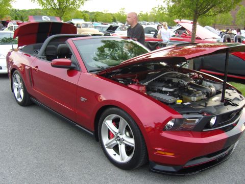 2007 Ford Mustang - A red 2007 Ford Mustang GT convertible is displayed with its hood and trunk open at a car show.