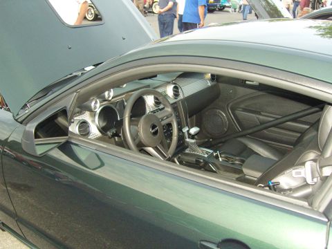 2007 Ford Mustang - Interior view of a green 2007 Ford Mustang, a roll bar and racing seatbelt.