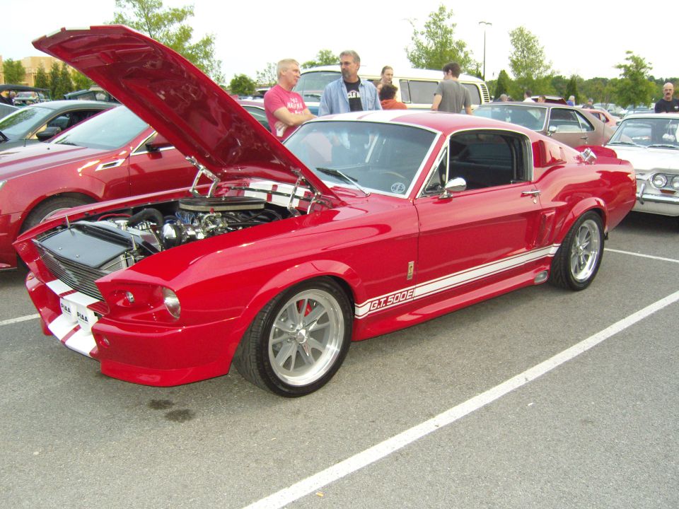 Red 1967 Ford Mustang GT500 with hood open, showing engine. White racing stripes on hood and side
