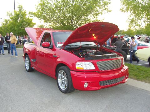 2007 Ford Mustang - A red Ford F-150 SVT Lightning pickup truck is displayed with its hood open at a car show.