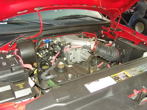2007 Ford Mustang - Close-up view of a vehicle's engine bay, highlighting a supercharger and various hoses and wiring.