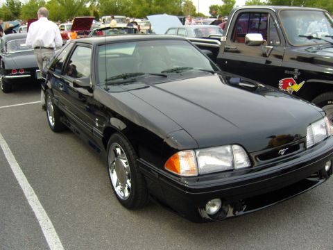 2007 Ford Mustang - A black coupe is parked at an outdoor event with other vehicles and people around.