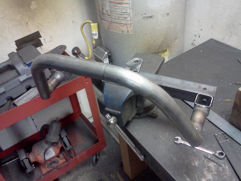 1999 Ford Ranger - A metal exhaust pipe section is secured in a vise, ready for modification in a workshop setting.