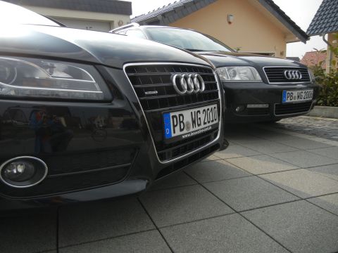 2010 Audi A4 - Two black Audi sedans are parked on a tiled driveway in front of a house.