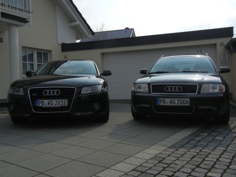 2010 Audi A4 - Two black Audi sedans are parked in front of a garage, one with a 2010 license plate.