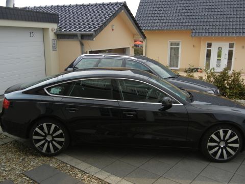2010 Audi A4 - A black Audi A5 Sportback is parked in front of a house, with another vehicle behind it.