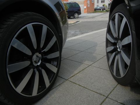 2010 Audi A4 - Two custom alloy wheels are visible, parked on a tiled walkway with a street and buildings in the background.