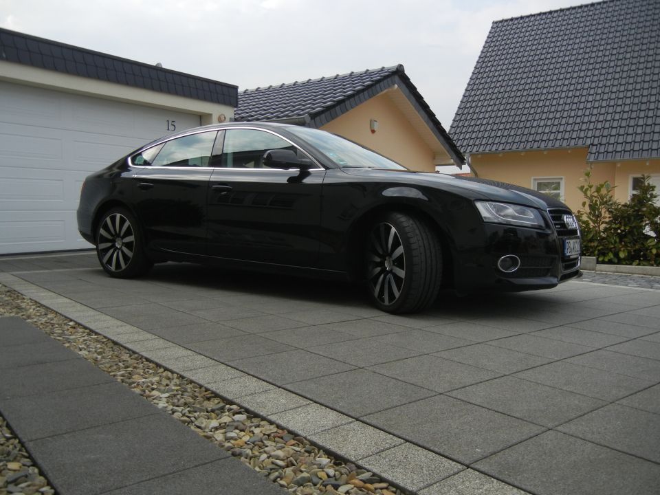 Black Audi sedan parked in front of a garage and house