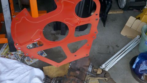 1978 Ford Bronco - A close-up of an orange engine component and a transmission, likely part of a vehicle repair or rebuild project.