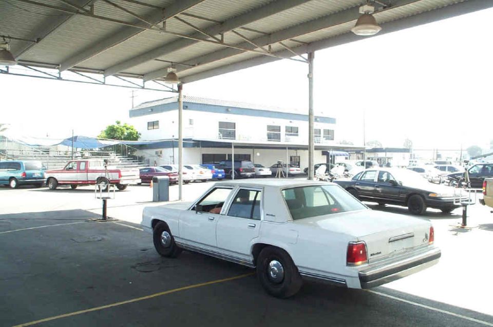 1991 Ford Crown Victoria LTD sedan parked under a canopy, other vehicles visible in background