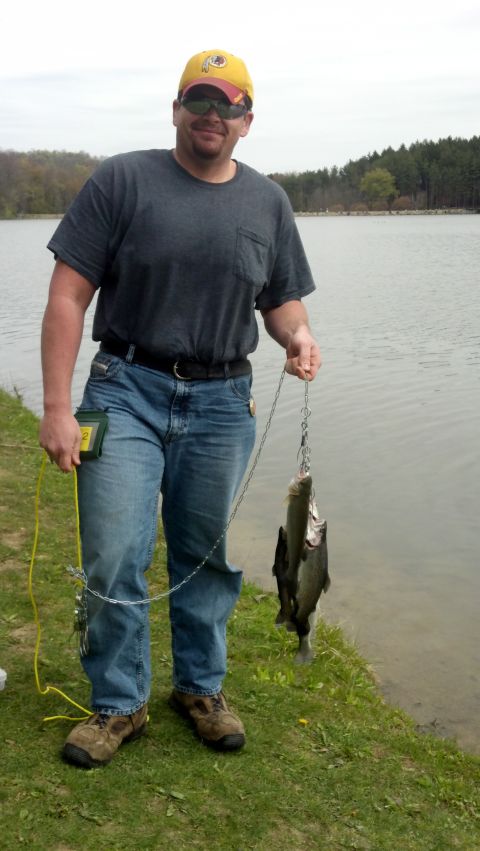 2004 Aston Martin Virage - A man stands by a lake, holding a string of freshly caught fish.