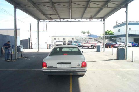 1991 Ford LTD Crown Victoria - Rear view of a silver sedan parked under a carport with other vehicles visible in the background.