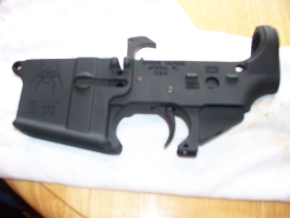Black AR-15 lower receiver with spider logo and text