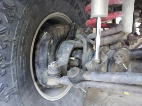 1978 Ford Bronco - Detail of a vehicle's front suspension and tire, showing mechanical parts and wear.