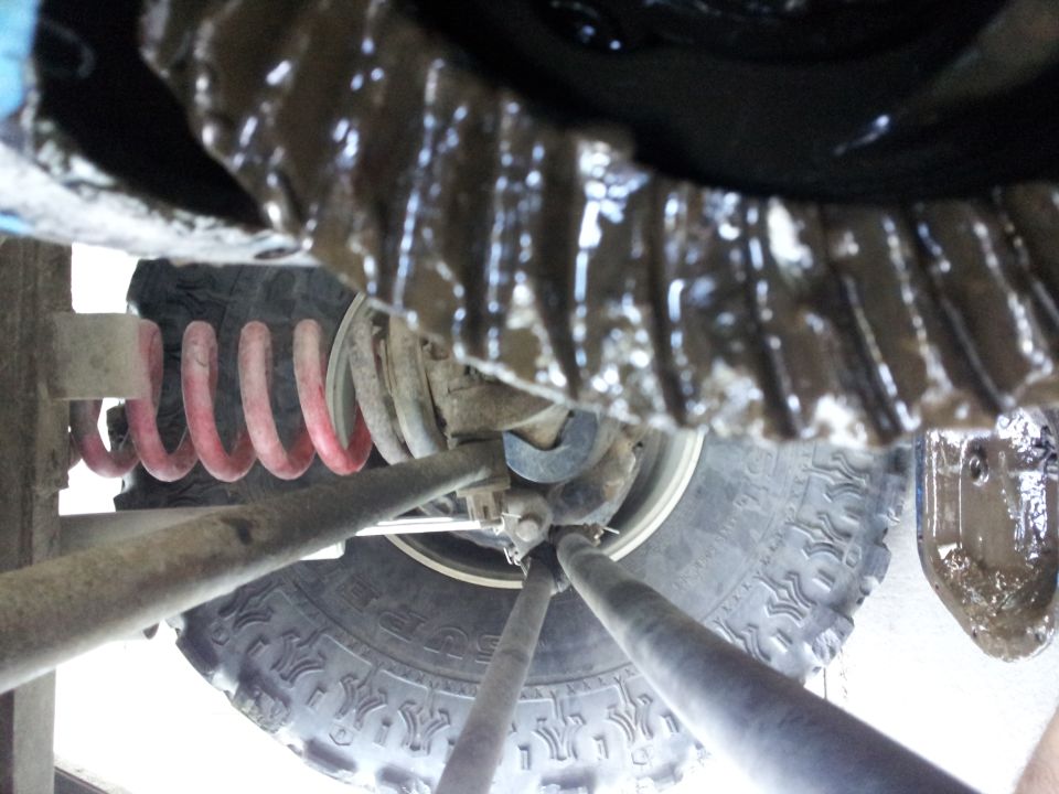 Underside view of a vehicle's differential, coil spring, and tire