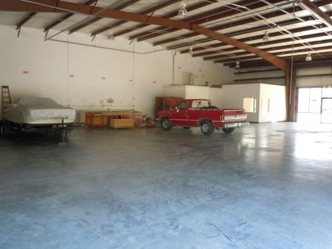 1980 Pontiac Trans Am - A red pickup truck sits inside a large warehouse with its hood open, next to a covered object on a trailer.