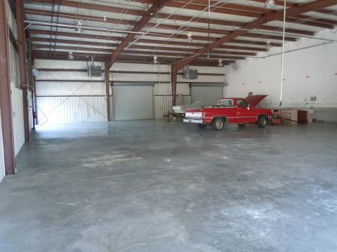 1980 Pontiac Trans Am - A red pickup truck is parked inside a large warehouse with its hood open.
