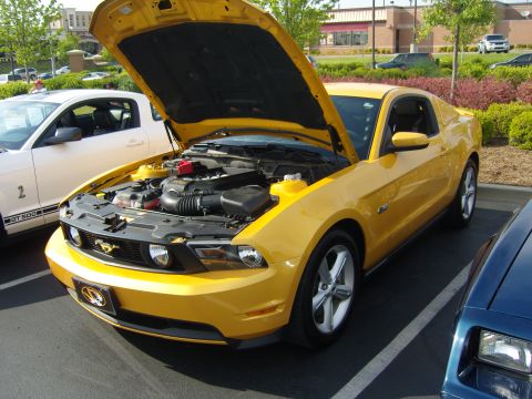 2007 Ford Mustang - A yellow Ford Mustang is parked with its hood up, showing the engine compartment.