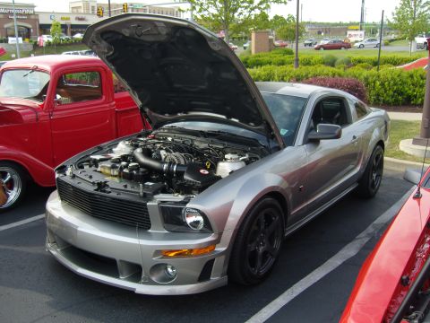 2007 Ford Mustang - A silver 2007 Ford Mustang is parked with its hood open, showing the engine bay.