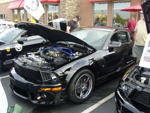 2007 Ford Mustang - Black 2007 Ford Mustang GT with custom engine components on display at a car show.