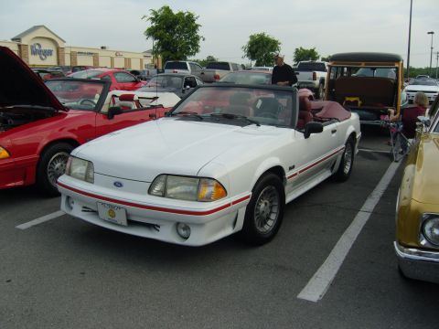 2007 Ford Mustang - A white convertible Mustang is parked in a lot with other vehicles.