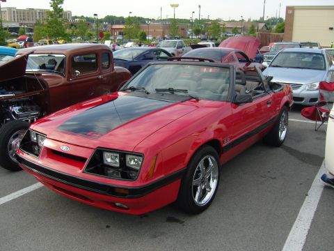 2007 Ford Mustang - This red convertible Mustang features a black hood stripe and GT badging, likely from the late 1980s.