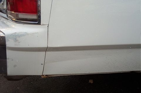 1991 Ford LTD Crown Victoria - Detail shot of a white vehicle's rear quarter panel, with visible water spots and minor damage.