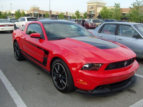 2007 Ford Mustang - A red Ford Mustang with a black stripe down the hood and roof is parked in a shopping center lot.