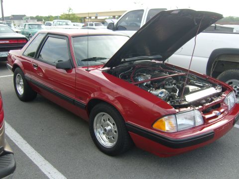 2007 Ford Mustang - A red coupe with its hood open is parked in a lot, revealing the engine compartment.