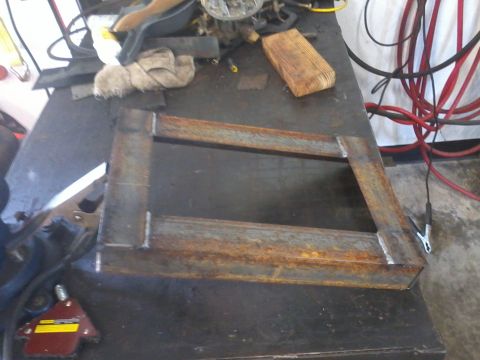 1995 Ford F-150 - A fabricated metal frame sits on a workbench, showing signs of rust and welding.