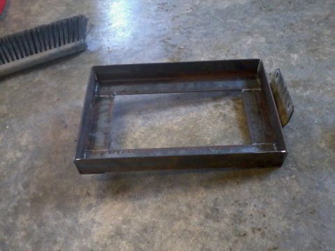 1995 Ford F-150 - A metal dual battery tray with an isolator is shown on a concrete floor next to a brush.
