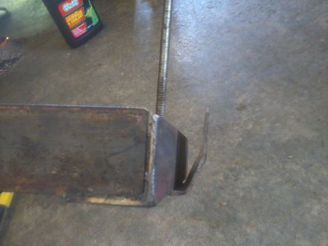 1995 Ford F-150 - A metal bracket and threaded rod are shown on a concrete surface, with a bottle of fluid nearby.