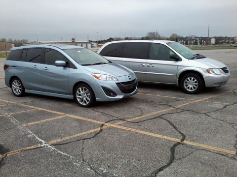 2012 Mazda Mazda 5 - A light blue 2012 Mazda Mazda 5 is seen parked next to a silver minivan in a parking lot.