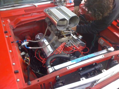 1964 Ford Ranchero - Mechanic works on the engine of a 1964 Ford Ranchero, a dual carburetor setup.