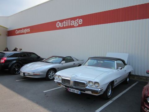 1991 Ford LTD Crown Victoria - A white convertible, likely from the early 1970s, is parked with its hood open next to a silver sports car.