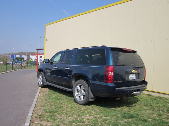 Dark blue Chevrolet Suburban parked on grass, rear view. License plate reads '059-ST'