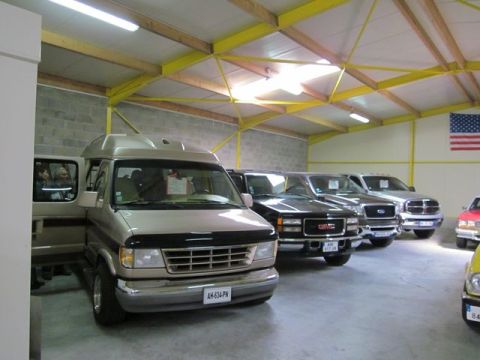 1991 Ford LTD Crown Victoria - Several vehicles are parked inside a garage, including a tan van with its door open.