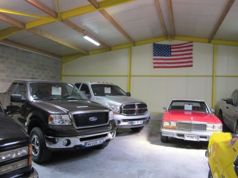 1991 Ford LTD Crown Victoria - Multiple vehicles are parked inside a garage, with an American flag displayed on the wall.