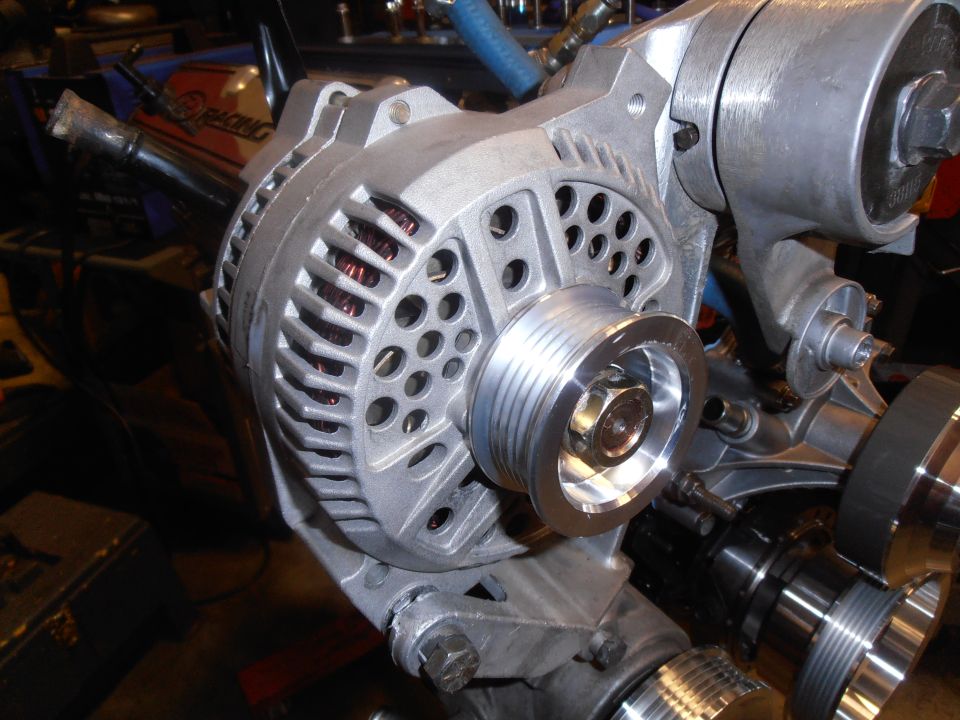 close-up of an alternator with a pulley attached, part of an engine assembly