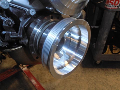 1990 Ford Bronco - Close-up of a shiny, multi-groove engine pulley mounted on a black engine block.