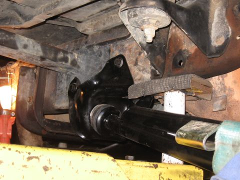 1994 Ford Bronco - Close-up of a vehicle's undercarriage, focusing on a black suspension component, likely during maintenance or repair.