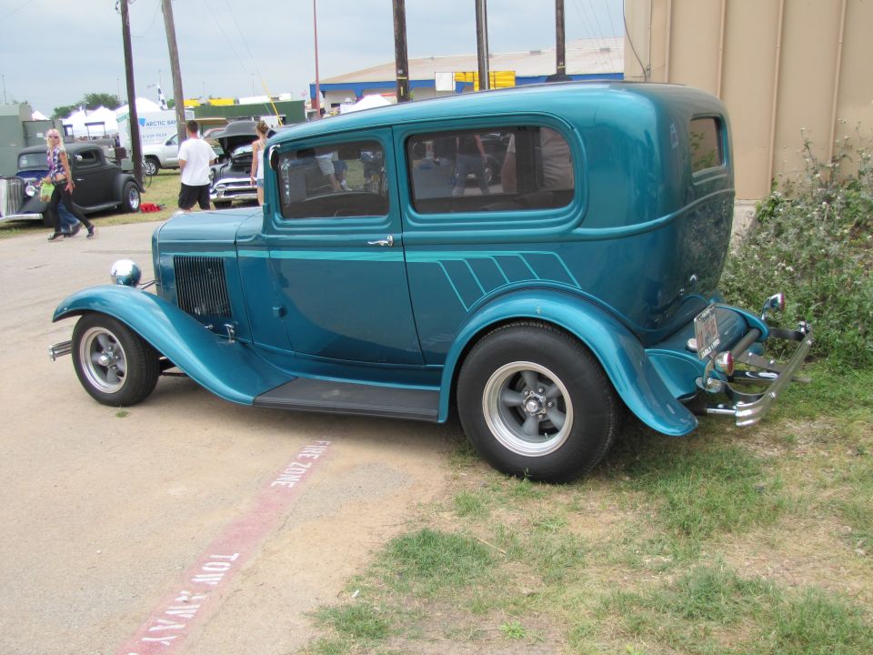 Teal hot rod sedan with custom pinstriping on rear fender, chrome bumper, and aftermarket wheels