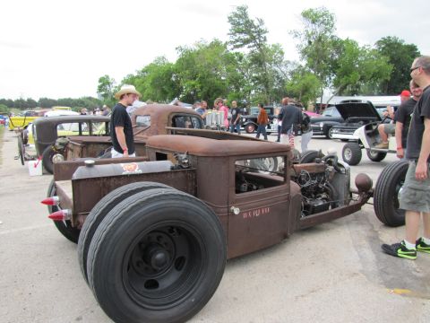 2006 BMW 5 Series - A heavily modified rat rod truck is displayed at an outdoor car show with other vehicles and spectators.