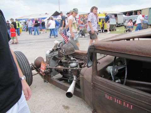 2006 BMW 5 Series - A heavily customized rat rod with a skull helmet and exposed engine is displayed at an outdoor event.