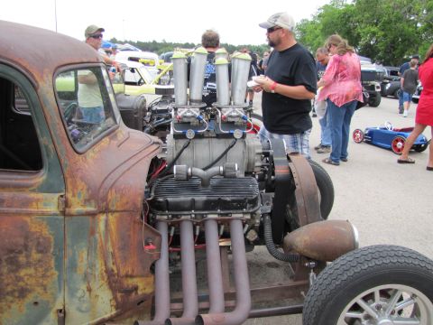 2006 BMW 5 Series - A heavily modified hot rod with a prominent supercharger and exhaust pipes is on display at an outdoor event.