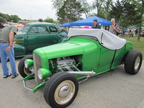 2006 BMW 5 Series - A bright green hot rod roadster is parked next to a classic green sedan at an outdoor car show.